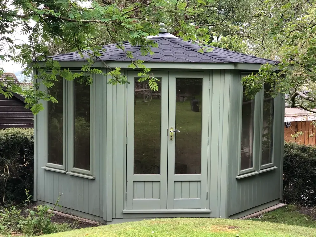 LANCASHIRE SUMMERHOUSES THIS PHOTO SHOWS A CORNER SUMMERHOUSE WITH A VAULTED ROOF WITH KATEPAL FELT TILED FINISH TO ROOF PAINED EXTERIOR